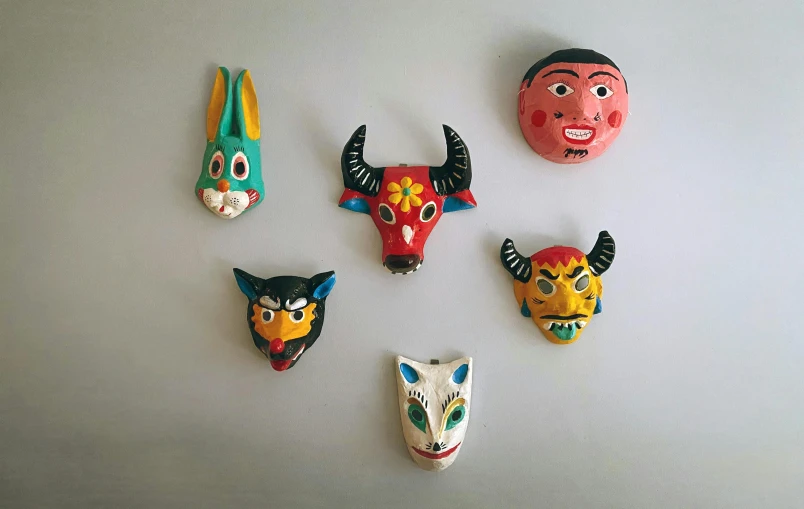 a bunch of masks hanging on a wall, by Tom Wänerstrand, folk art, modelling clay, flatlay, draconians, 60s