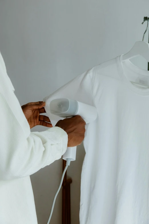 a person ironing a white shirt on a hanger, wearing a white sweater, detailed product image, zoomed in, white uniform