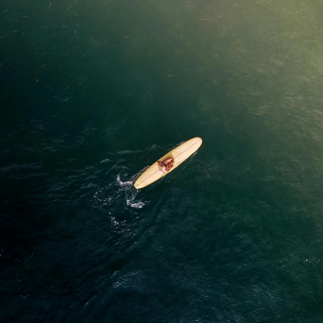 a person riding a surfboard on top of a body of water, by Elsa Bleda, pexels contest winner, wooden boat, aerial footage, single light, ignant