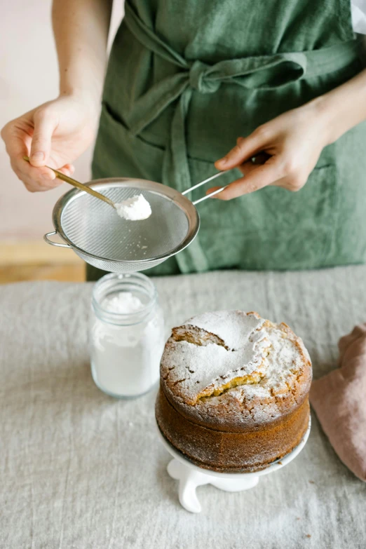 a woman is decorating a cake on a table, by Lucette Barker, trending on unsplash, renaissance, powdered sugar, high quality product photo, epicurious, grain”