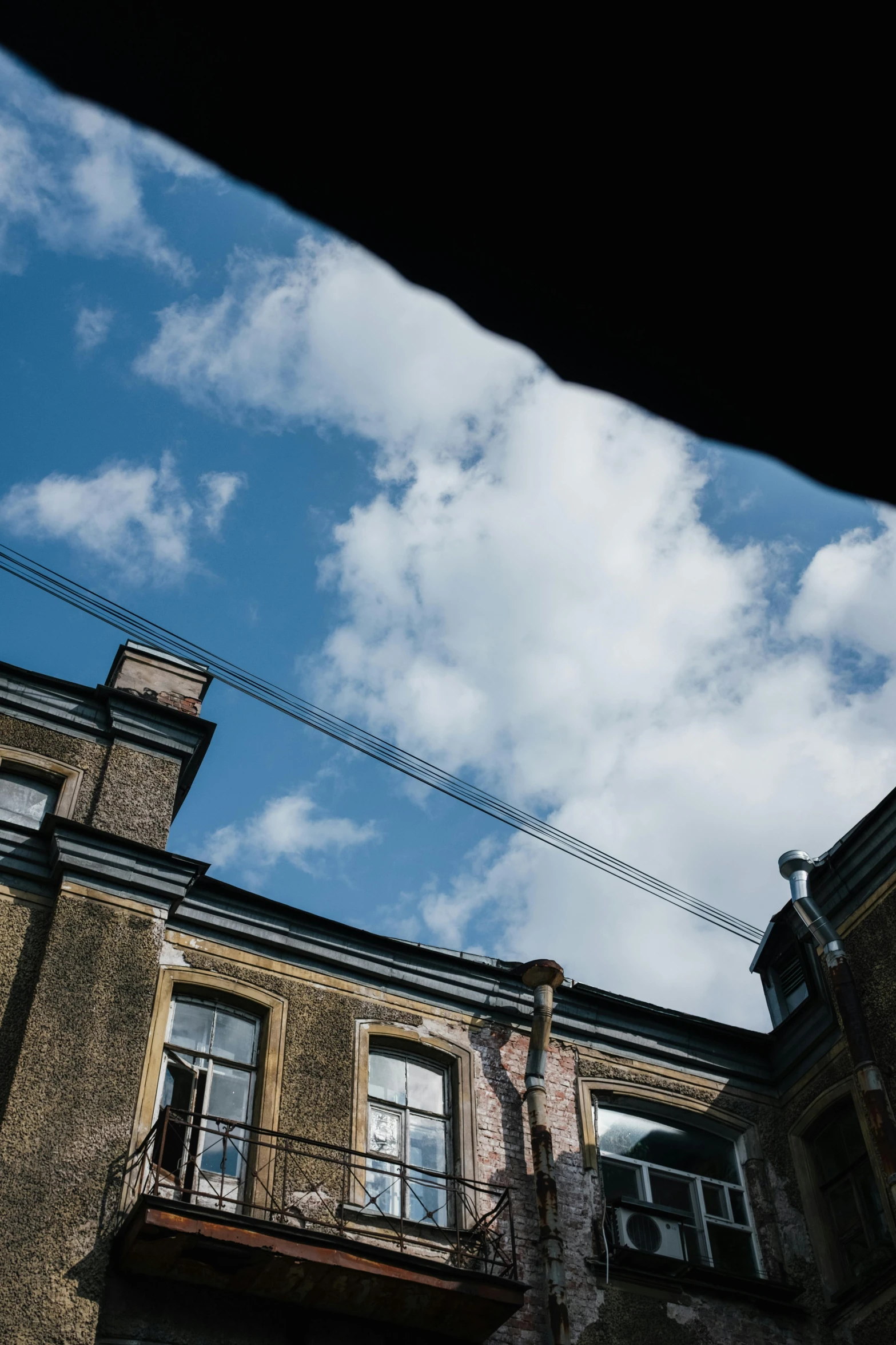 a clock on a pole in front of a building, an album cover, inspired by Leandro Erlich, unsplash, barbizon school, view from below, an abandonded courtyard, steam clouds, taken from the high street
