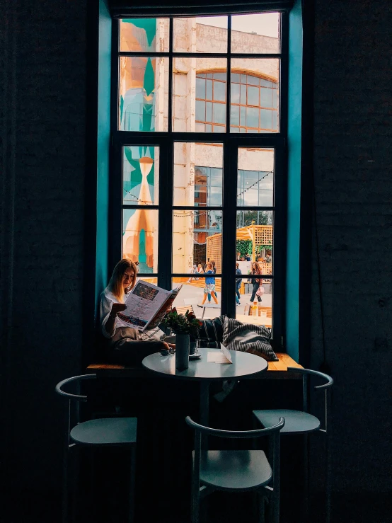 a person sitting at a table reading a book, by Jan Tengnagel, pexels contest winner, visual art, bars on the windows, in chippendale sydney, aquamarine windows, gif