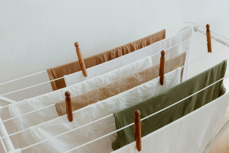 a close up of clothes hanging on a clothes rack, inspired by Ceferí Olivé, organic color, white sheets, green and brown clothes, japanese collection product