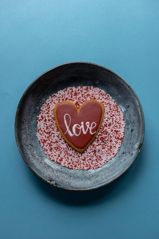 a heart shaped cookie on a plate with sprinkles, a picture, by Anna Findlay, pexels, graffiti, red dish, slate, thumbnail, 8