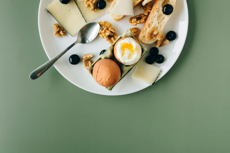 a white plate topped with different types of food, a still life, pexels contest winner, eating cheese, silver egg cup, background image, muted green