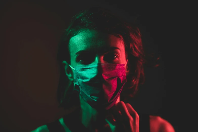 a woman wearing a face mask in the dark, pexels contest winner, antipodeans, green and red, avatar image, cyan and magenta, desaturated