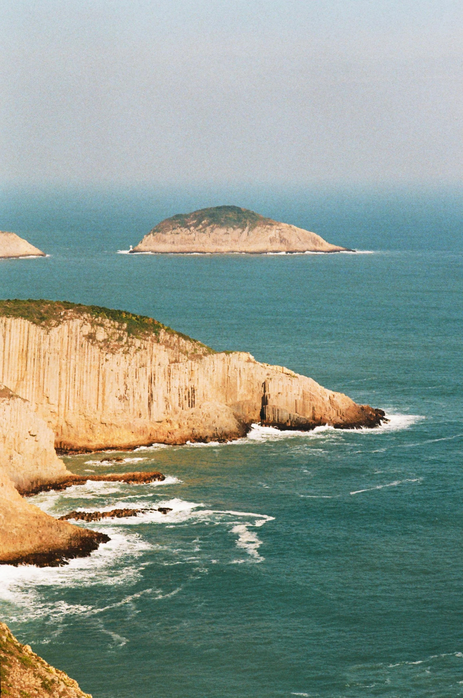 a group of people standing on top of a cliff next to the ocean, jin shan, two medium sized islands, slide show, overview