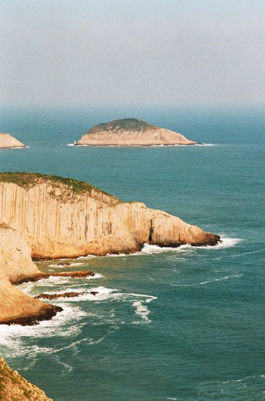 a group of people standing on top of a cliff next to the ocean, jin shan, two medium sized islands, slide show, overview