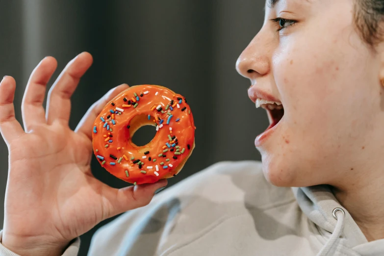 a close up of a person holding a doughnut with sprinkles, pexels contest winner, hyperrealism, overweight!! teenage boy, an orange, large gaping mouth, avatar image