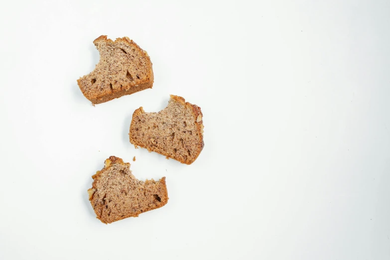 a piece of bread with a bite taken out of it, unsplash, figuration libre, three views, background image, debris spread, grain”