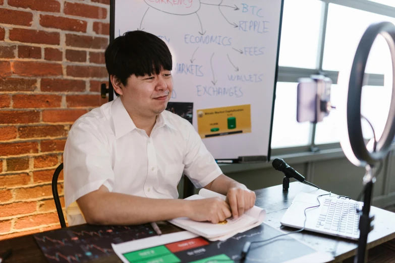 a man sitting at a table in front of a laptop, by Jang Seung-eop, jontron, in a classroom, avatar image