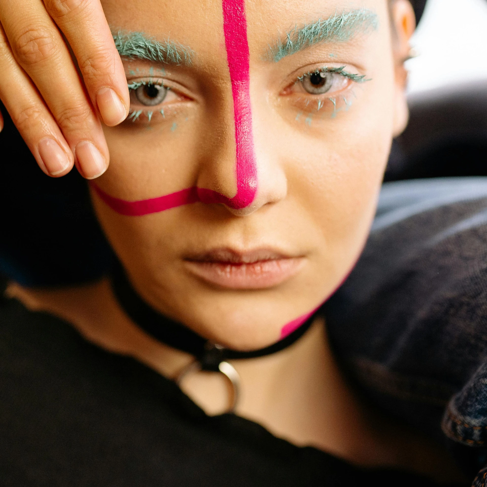 a close up of a person with a painted face, pink and teal, markings on her face, woman model, making of