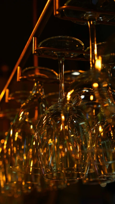 a bunch of wine glasses hanging from a bar, inspired by Bruce Munro, pexels, gold fractal details, shot on sony a 7, low detail, filmstill