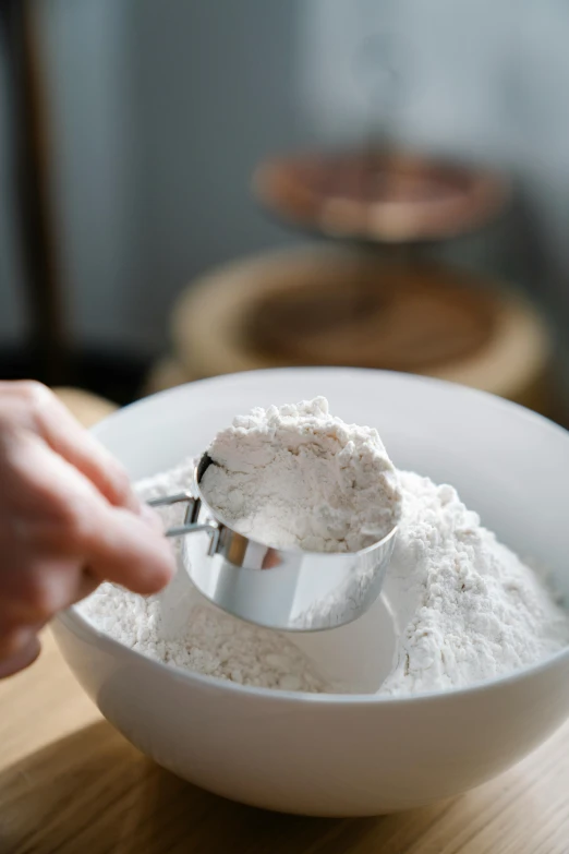 a person scooping flour into a bowl, inspired by Yukimasa Ida, unsplash, silver，ivory, dynamic closeup, multiple stories, product introduction photo