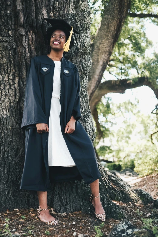 a woman in a graduation gown leaning against a tree, unsplash, renaissance, off - white collection, long black jacket, maria borges, dwell