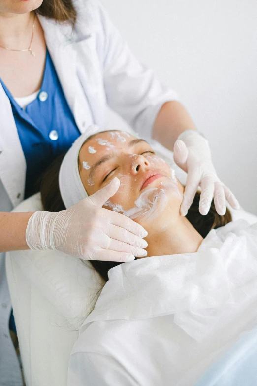 a woman getting a facial mask at a beauty salon, by Adam Marczyński, face scars, square facial structure, medical, petite