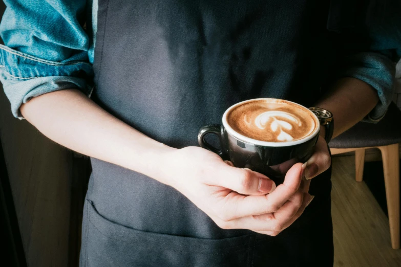 a close up of a person holding a cup of coffee, wearing an apron, latte art, multiple stories, premium quality