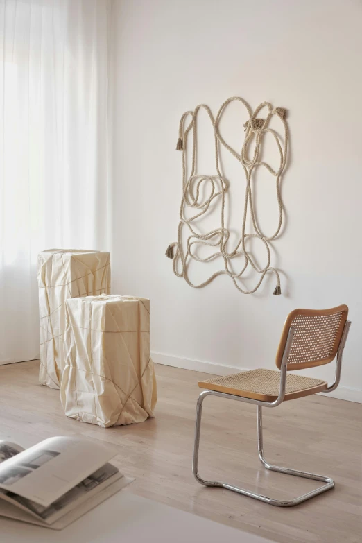 a living room filled with furniture and a large window, an abstract sculpture, inspired by Sarah Lucas, braided cable, light - brown wall, subject made of white mesh rope, linen canvas