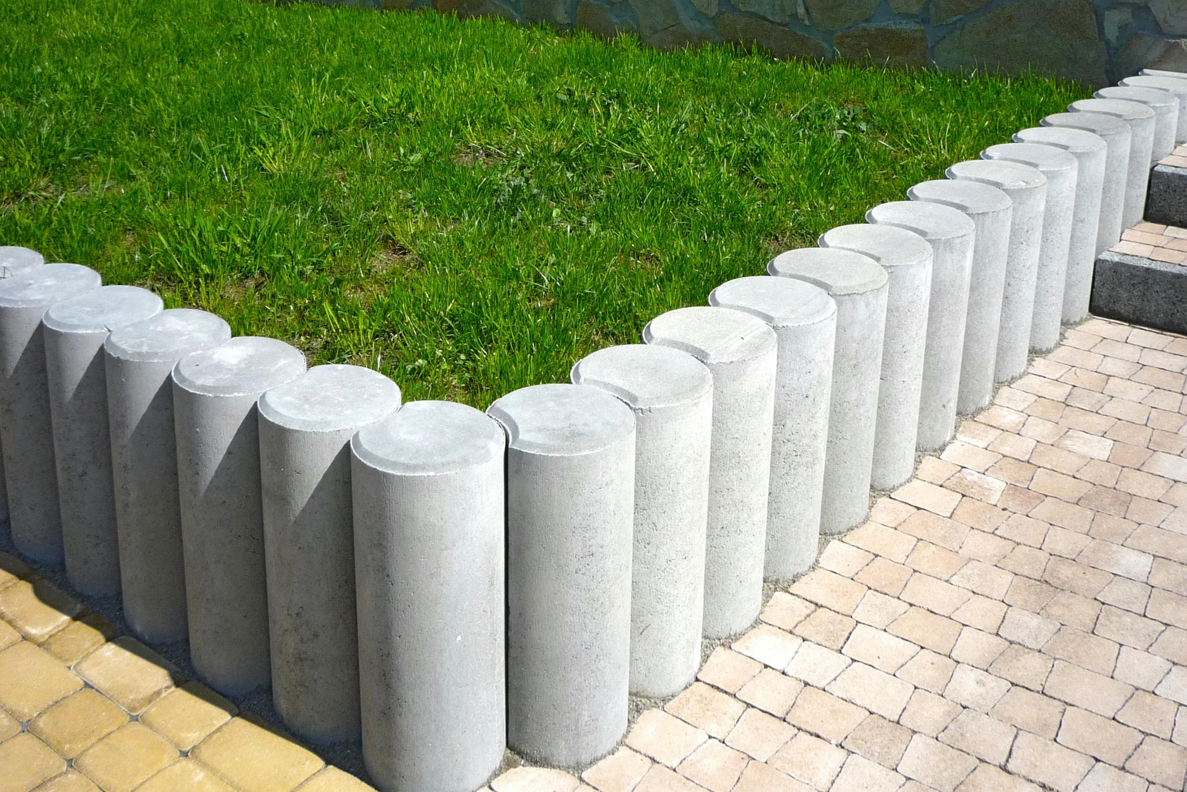 a row of concrete pillars sitting on top of a lush green field, concrete art, modular item, round jaw, easy to use, grey