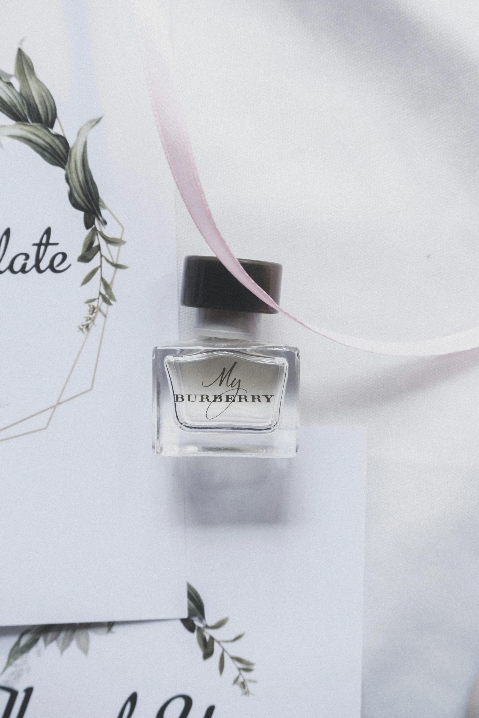 a bottle of perfume sitting on top of a table, a picture, white ribbon, thumbnail, burberry, nail polish