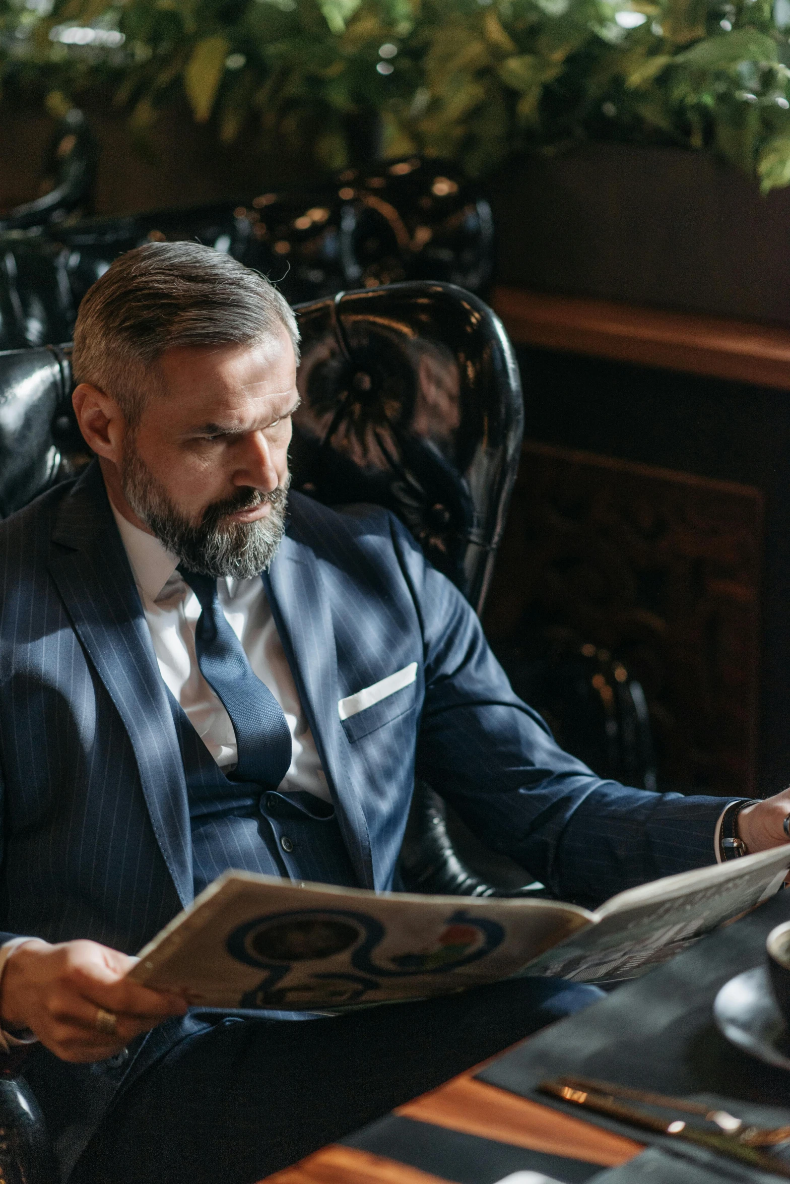 a man sitting at a table reading a newspaper, a portrait, by Drew Tucker, pexels, fine art, luxurious suit, greybeard, executive industry banner, 15081959 21121991 01012000 4k