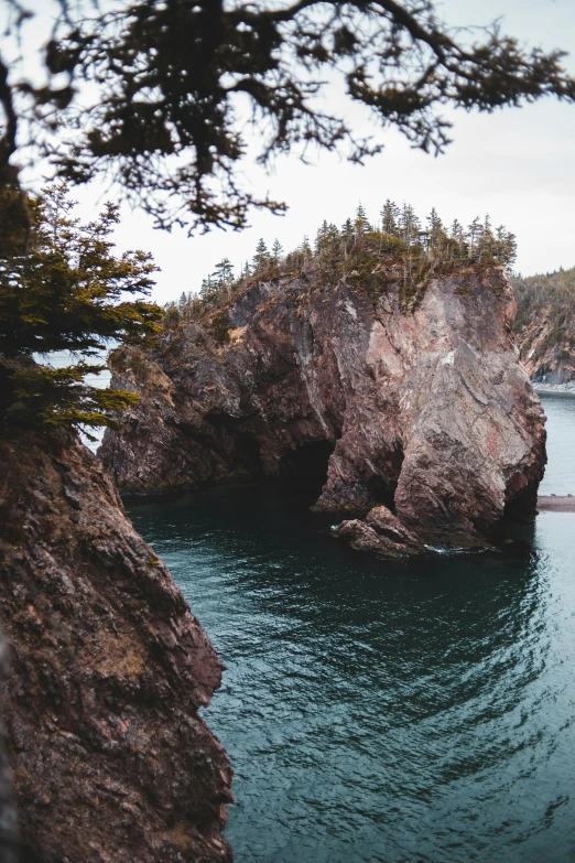 a large body of water surrounded by trees, by Jessie Algie, unsplash contest winner, coastal cliffs, igneous rock, rock arches, slide show