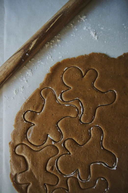 a cookie sitting on top of a cutting board next to a wooden spoon, a jigsaw puzzle, by Jessie Algie, gingerbread people, ffffound, dwell, thumbnail