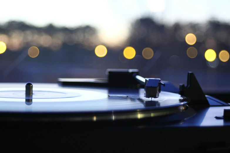 a close up of a turntable with lights in the background, an album cover, unsplash, evening at dusk, classical, unblur, various artists