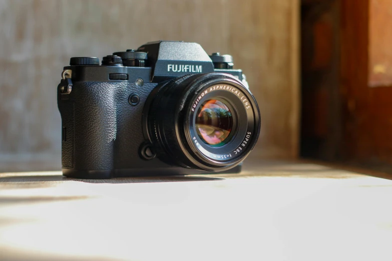 a black camera sitting on top of a table, a picture, by Julia Pishtar, unsplash, photorealism, fujifilm x - h 2 s, 6 0 mm lens in full armor, medium format. soft light, camera on the ground