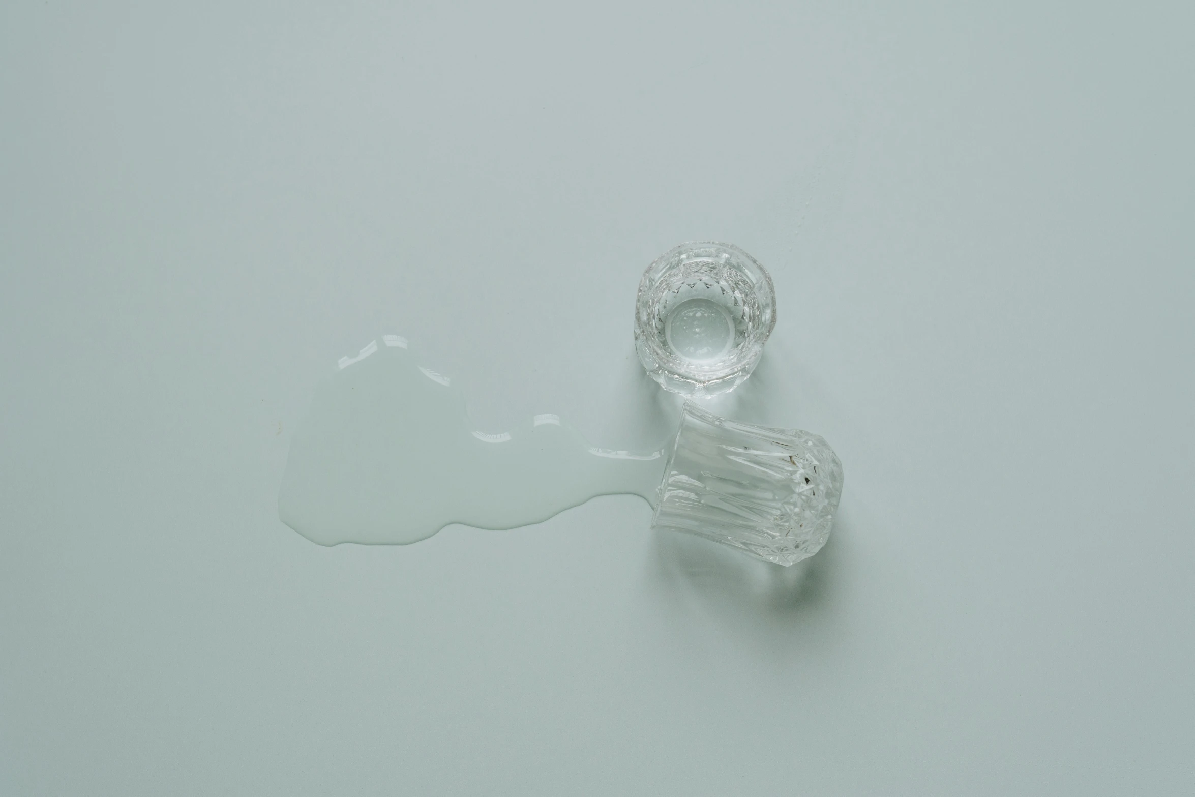 a close up of a glass object on a table, inspired by Lucio Fontana, unsplash, spilled milk, plain background, clear figures, ignant