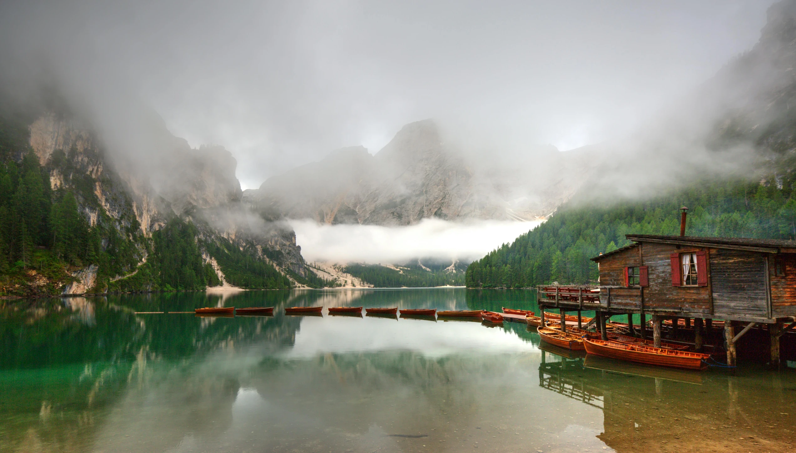 a boat dock in the middle of a lake with mountains in the background, by Bernardino Mei, pexels contest winner, romanticism, lago di sorapis, low clouds after rain, panels, conde nast traveler photo