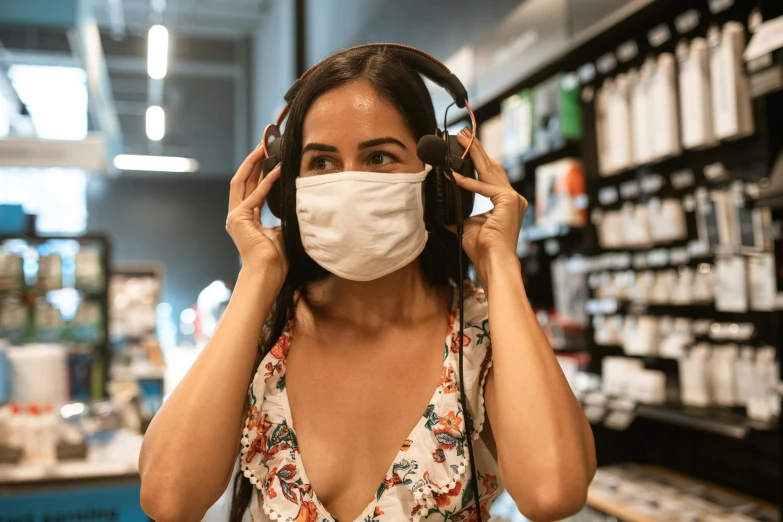 a woman wearing a mask and headphones in a store, trending on pexels, fan favorite, stood in a lab, bottom angle, holding close