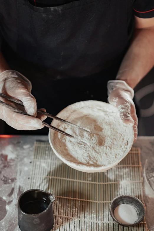 a person holding a pair of scissors over a bowl of food, covered in white flour, sake, sculpted, yeast