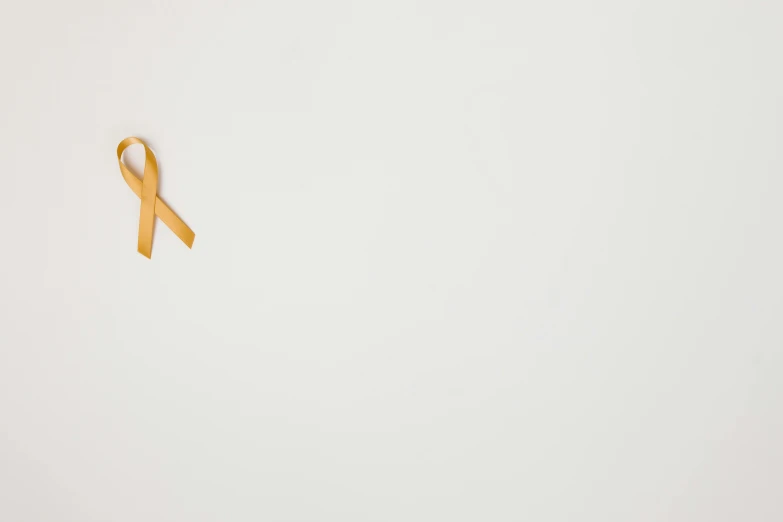 a yellow ribbon on a white background, a picture, by Gavin Hamilton, pexels, background image, tumours, golden accents, healthcare