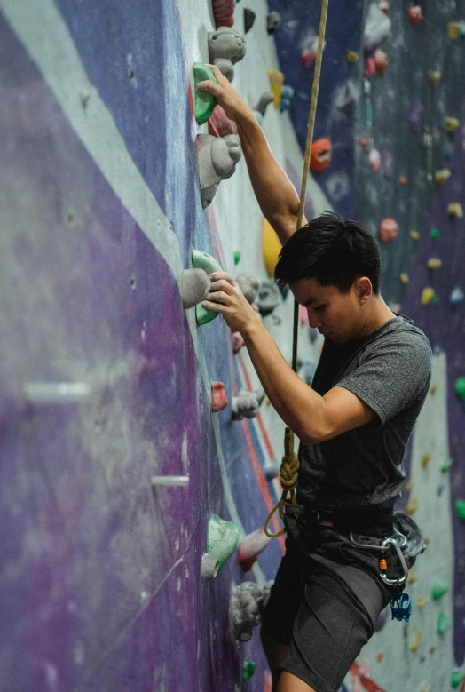 a man climbing up the side of a climbing wall, a portrait, pexels contest winner, asian male, purple, promo image, mechanics