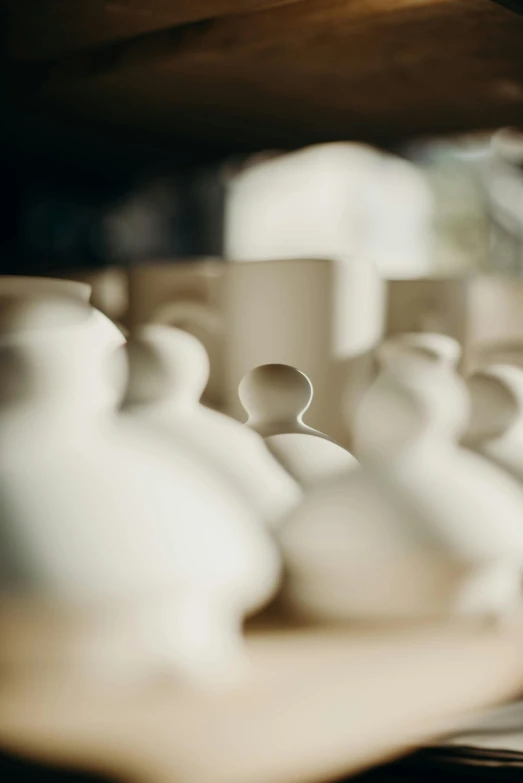 a bunch of white vases sitting on top of a shelf, by Jessie Algie, unsplash, process art, hooded figures, warm shading, small manufacture, up-close