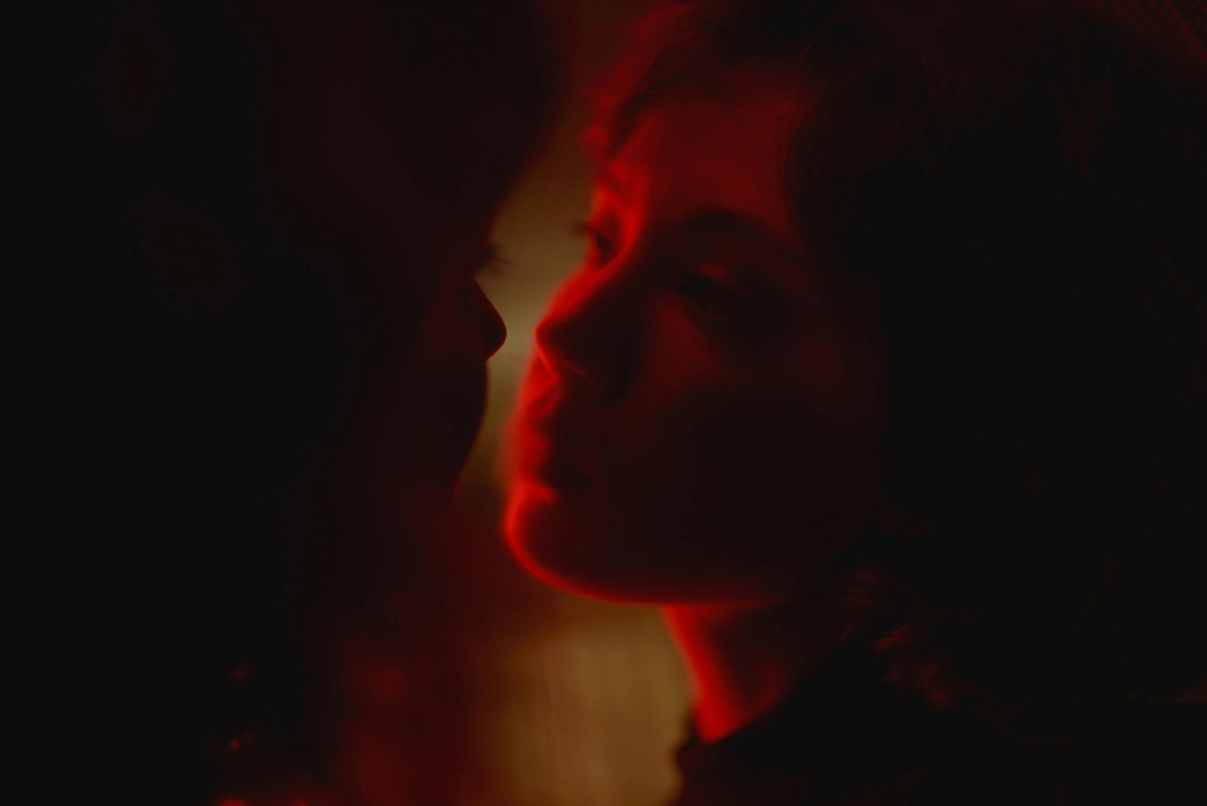 a woman standing in front of a red light, inspired by Nan Goldin, realism, reylo kissing, movie still from game of thrones, embers, two women