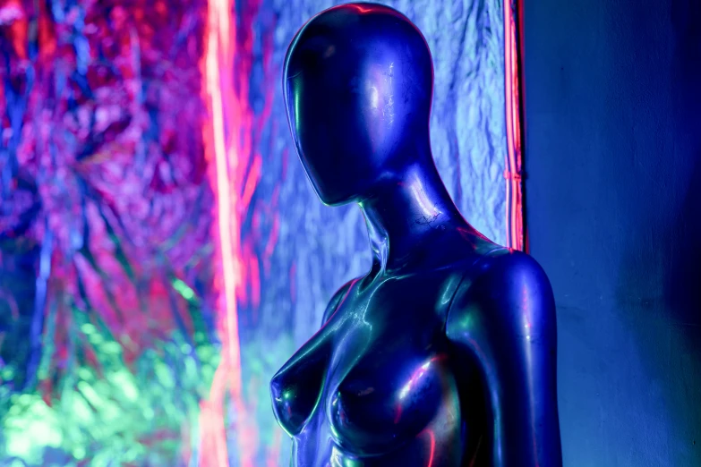 a close up of a mannequin with neon lights in the background, an abstract sculpture, holography, blue body paint, adult video store, bronze statue and silver, latex shiny