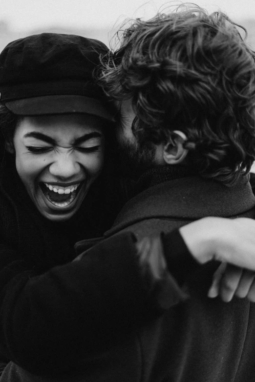a couple of people that are hugging each other, a black and white photo, by Niko Henrichon, pexels contest winner, dark short curly hair smiling, open happy mouth, photography from vogue magazine, girl
