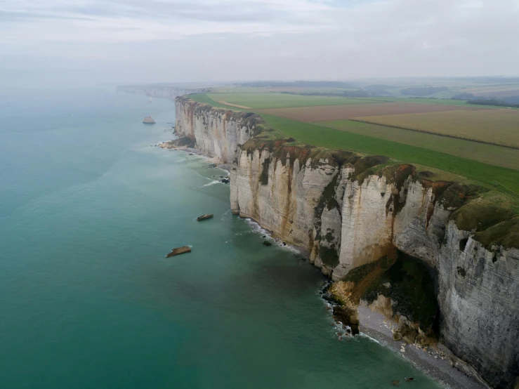 a large body of water next to a cliff, by Raphaël Collin, pexels contest winner, renaissance, the normandy landings, limestone, breitling, dezeen