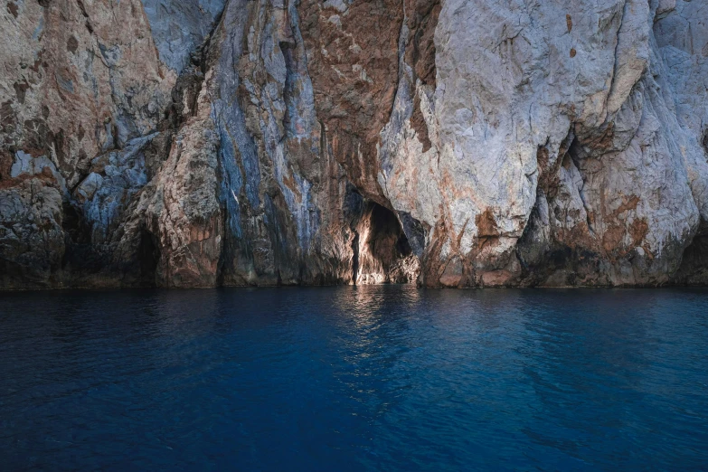 a cave in the middle of a body of water, dark blue water, piroca, full colour, thumbnail