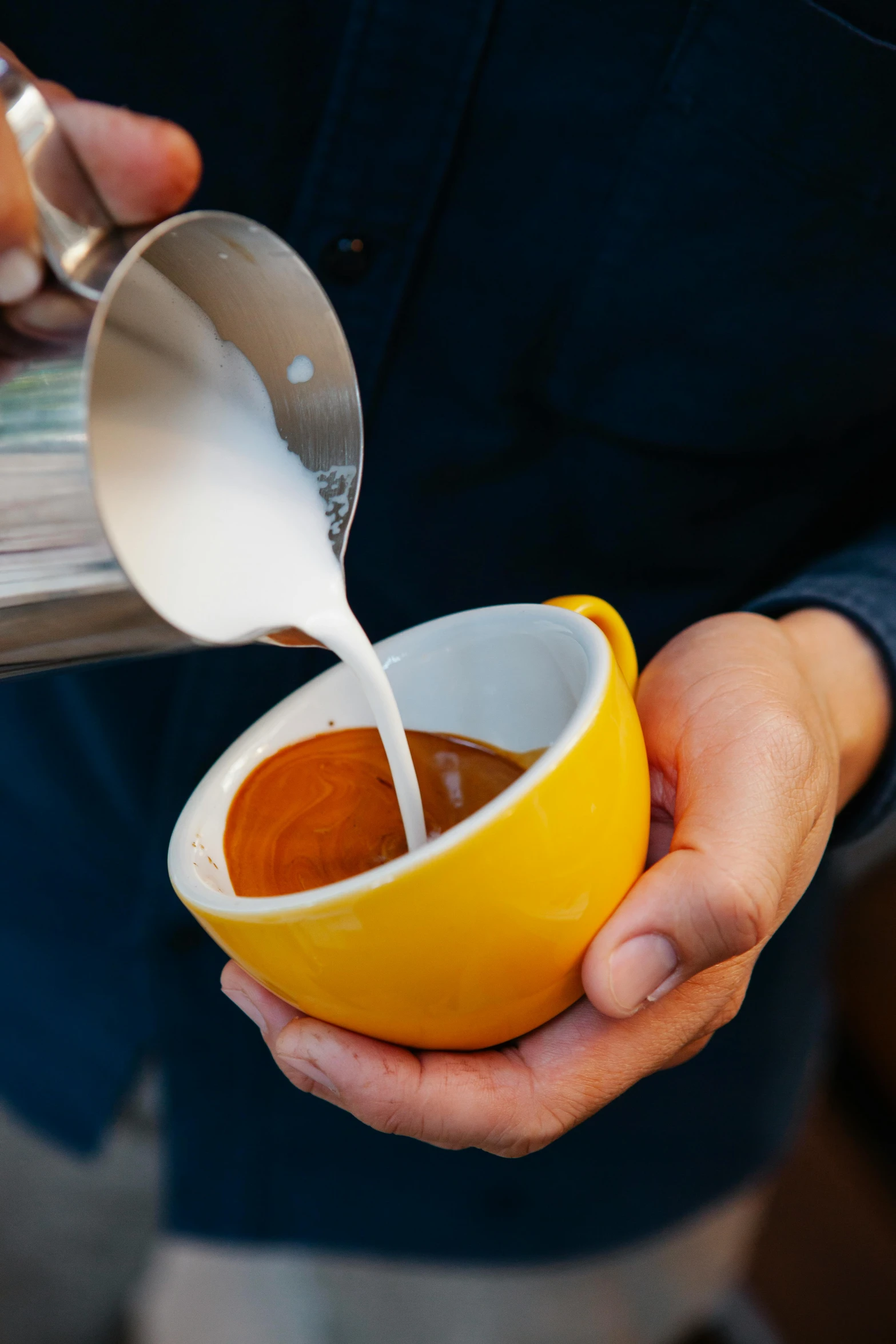 a person pouring milk into a cup of coffee, by Doug Ohlson, mustard, exterior shot, square, no cropping