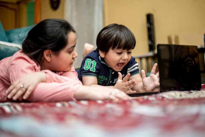 two children laying on the floor looking at a laptop, a portrait, pexels contest winner, egypt, avatar image, teaching, high resolution photo