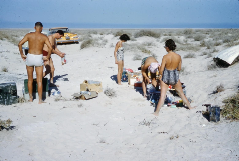 a group of people standing on top of a sandy beach, a colorized photo, gutai group, hunting, kombi, gulf, jock