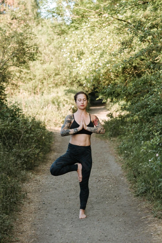 a woman doing a yoga pose on a dirt road, unsplash, person made of tree, low quality photo, tattooed, neoprene