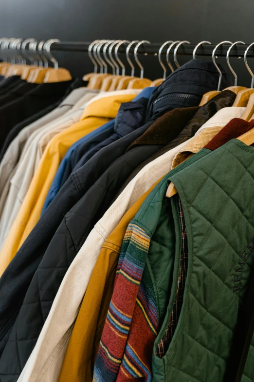 a row of clothes hanging on a rail, by Nina Hamnett, trending on unsplash, wearing green jacket, dressed in 1970s menswear, yellow clothes, inspect in inventory image