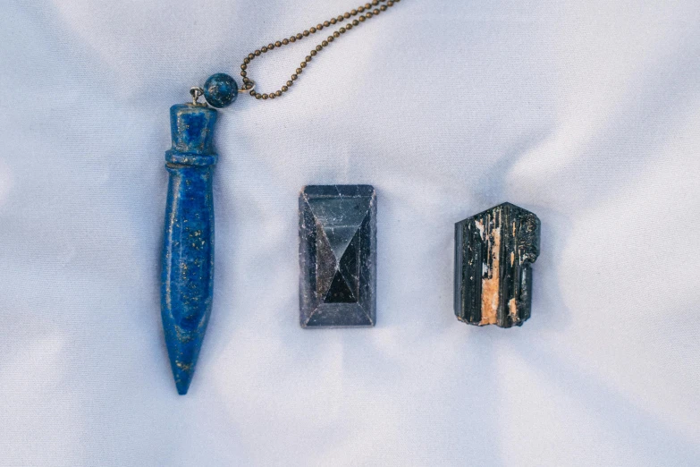 a couple of items sitting on top of a white sheet, unsplash, crystal cubism, lapis lazuli, historical photo, pendants, blue-black