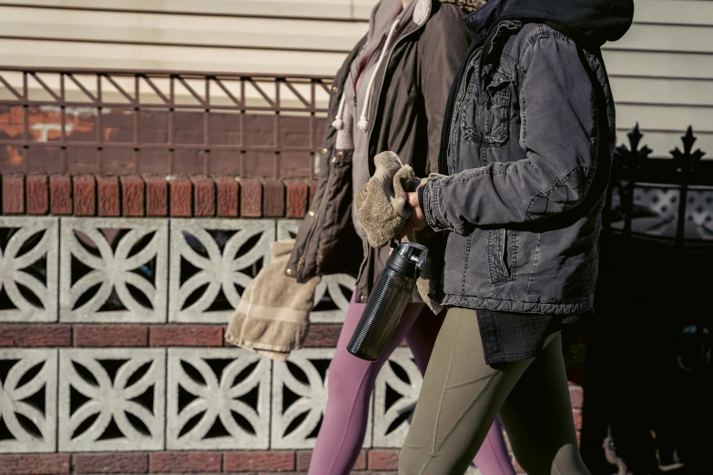 a man and a woman walking down a sidewalk, inspired by Louis Stettner, trending on unsplash, graffiti, carrying a scoped hunting rifle, water bottles, detail shot, woman holding another woman