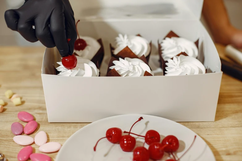 a box of cupcakes sitting on top of a table, cherries, profile image