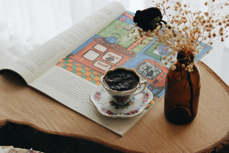 a book sitting on top of a table next to a cup of coffee, a picture